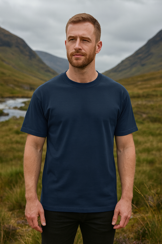 Man wearing a glen ogal organic cotton navy blue t-shirt standing in a mountainous landscape